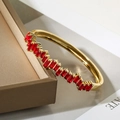 Dettaglio di un bracciale dorato con zirconi rossi rettangolari su una scatola da regalo - Rettangolo Rosso