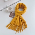 Flat lay of a knotted yellow cashmere-feel scarf with tassels and a ceramic cup - Regular Fit / Ginger Yellow