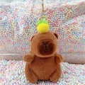 Brown capybara plush keychain with a colorful pom-pom hat and golden metal ring - Dark Brown Pineapple + Gold Clip