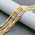 Macro shot of 4mm faceted strawberry glass beads in amber and cream on a grey display - Mixed Color 8