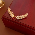 Macro shot of gold wheat ear earrings with sparkling zircons and pearls on a wooden box - Ear Hook Style / Gold