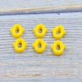 Macro shot of six yellow synthetic opal Hamsa hand beads for DIY jewelry on wood - Yellow