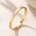 Macro detail of golden stainless steel bracelet with geometric pattern and glossy finish - Gold