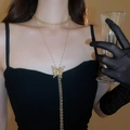 Detailansicht eines mehrlagigen Gold-Schmetterlingsanhängers an einem Model im Vintage-Stil - Gold Schmetterling Zirkonia Quaste Körperkette