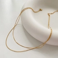 Detailed close-up of golden double-layer necklace featuring snake and cross chains - Gold O-Chain + Round Snake Chain