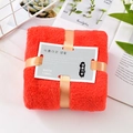 Thick red coral fleece bath towel folded with golden ribbon and grey brand label - Red