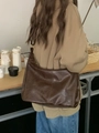 Detail van de grote donkerbruine leren hobo tas gedragen door een model in casual stijl - Bruin