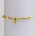 Detail of golden bead bracelet with an engraved letter R pendant on a white pedestal - Letter R (DB240603-R)