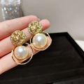 Dettaglio di orecchini vintage a disco dorato con grandi perle finte in mano - Perla Tonda (No.20)