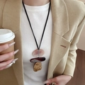 Detail of a three-layer geometric resin pendant necklace on a leather cord over a white top - Geometric (76# Necklace)