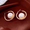 Macro shot of 18K gold plated horse-shaped earrings with round white pearls on silk - Gold Textured Hoop Pearl Earrings