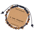 Détail d'un bracelet code Morse avec perles œil de tigre sur une carte en papier kraft - Nouveau Chapitre