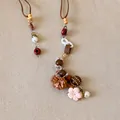 Détail d'un collier bohème vintage avec fleurs en tissu, perles colorées et breloques - Style Fleur en Tissu Coffee Believe