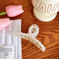 Elegant clear acrylic claw clip adorned with white pearls on a rustic wooden desk - No. 8 Cross Medium 7.3cm