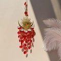 Close-up of golden sun and moon suncatcher with red crystal beads casting shadows - Red Sun