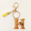 Close-up of letter H acrylic keychain with honey bee motif, yellow tassel, and lobster clasp - Letter H