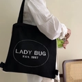 Detail of black canvas drawstring backpack with white Lady Bug Est. 1997 embroidery - LADY BUG Letters / Black with Letters
