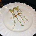 Elegant gold butterfly earrings with green zircon and long pearl tassel on a white dish - Zircon Pearl Butterfly Tassel Earrings