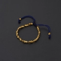 Detalle de pulsera tejida a mano azul marino con cuentas doradas irregulares - 33 Cuentas Irregulares