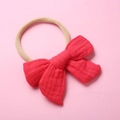 Detail of red muslin cotton bow with a beige elastic headband for newborn babies - Red
