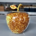 Close-up of decorative crystal apple with golden leaf and orange beaded interior detail - Yellow