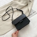 Minimalist black square crossbody bag with decorative chain strap on casual outfit - Black