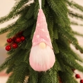 Close-up of a pink knitted gnome ornament hanging on a green Christmas tree branch - Knitted Hanging Pink Style C