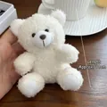 Detail view of 11cm white plush teddy bear brooch with soft curly fur and cute button eyes - Off White