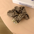 Brown plaid organza scrunchie hair tie with designer tag on a wooden surface - Dark Plaid