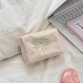 Detail of a cream canvas makeup bag with bow embroidery and top zipper closure - Beige