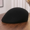 Close-up of black wool felt newsboy cap with smooth texture on dark wooden table - M (56-58cm) / Black