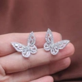 Close-up of silver butterfly earrings featuring hollow zircon inlay on hand - Small White Gold Butterfly