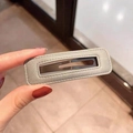 Close-up of a grey leather rectangular hair clip showing fine texture and brown metal clip - Off-White