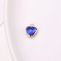 Blue crystal heart charm with golden copper edge and hanging loop on white tray - Sapphire Blue