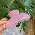 Pink acrylic large hair claw clip with glossy finish held against green plant background - 10cm Yuanbao Claw / Jelly Pink