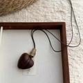 Détail d'un pendentif cœur en résine de bois marron foncé sur un plateau de présentation - 9# Collier-Café