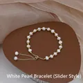 Elegant white freshwater pearl bracelet with adjustable golden slider chain on display - Drawstring Style / White
