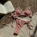 Macro-detail van roze gehaakte bikini met witte kant en strik op een sisalmat - S / Roze