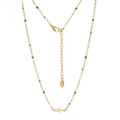 Close-up of golden Ankh necklace featuring green enamel beads and lobster clasp detail - Gold Spring Green Beads