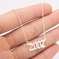 Macro shot of a silver 2007 birth year pendant in gothic font on a delicate chain - 2007 / Steel