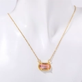Dettaglio di una collana dorata con ciondolo rettangolare in gemma rosa su un manichino - Rosa Trasparente (Aprile)
