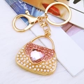 Elegant gold handbag keychain with pink heart crystal and pearls on soft plush background - Pink Pearl Heart Handbag Keychain