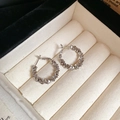 Detailopname van onregelmatige zilveren oorringen met facetkralen op een beige sieradendoosje - Onregelmatige Zilveren Getextureerde Ring (Zilveren Naald) / Zilver