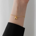 Minimalist gold snake chain bracelet with a lucky charm pendant on a model wrist - Bracelet-Gold (E55)