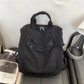Minimalist black washed canvas backpack for women featuring large front pocket and top handles - Black