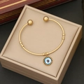 Dettaglio del bracciale in acciaio dorato con pendente malocchio su cuscino portagioie - Blu