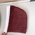 Détail du bonnet d'hiver bordeaux avec doublure en fausse fourrure blanche et glands colorés - Café avec bord blanc