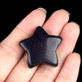 Polished blue goldstone star-shaped crystal held in hand with glittering starfield effect - Blue Sand Stone (Synthetic)