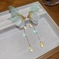 Detailaufnahme von Schmetterlings-Ohrringen mit grünen Flügeln und goldenen Quasten - Grün