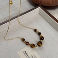 Macro shot of tiger eye beads and gold heart pendant on a chain in a jewelry display box - 65# Necklace-Gold-Brown (Gradient Tiger Eye Heart)